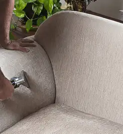 Professional upholstery cleaner deep-cleaning a fabric sofa with a handheld extraction tool and hose Omaha, NE.